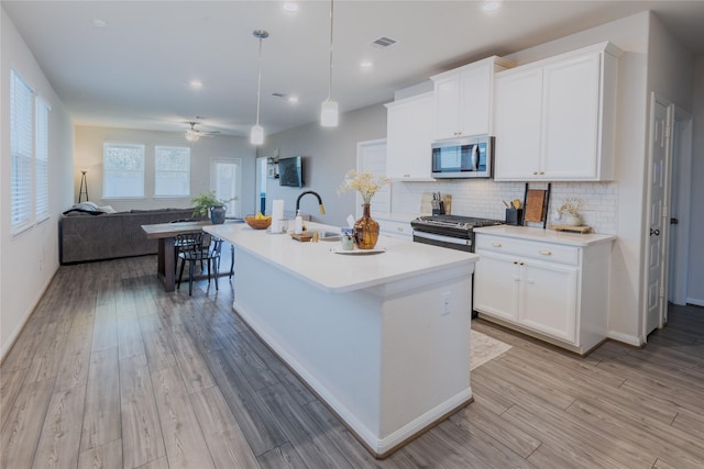 kitchen featuring tasteful backsplash, visible vents, appliances with stainless steel finishes, light wood-type flooring, and a sink