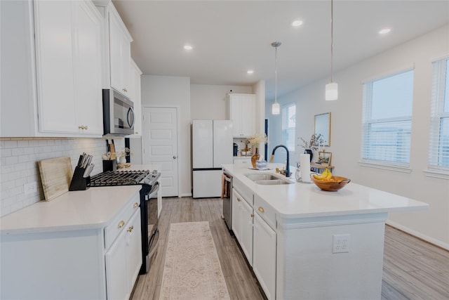 kitchen with light wood-style flooring, stainless steel appliances, a sink, light countertops, and decorative backsplash