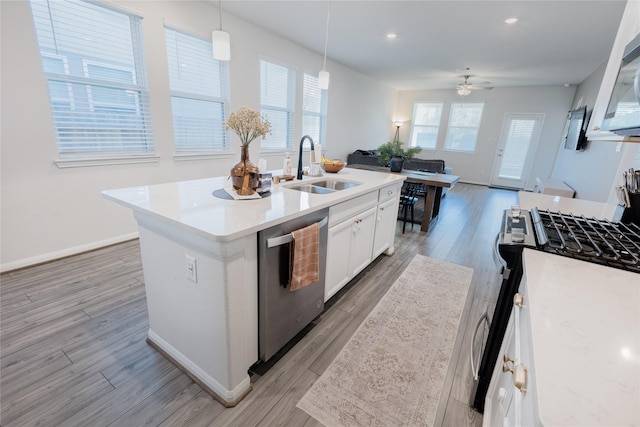 kitchen with stainless steel appliances, light wood-style floors, white cabinetry, and a sink