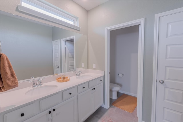 bathroom with toilet, tile patterned flooring, double vanity, and a sink