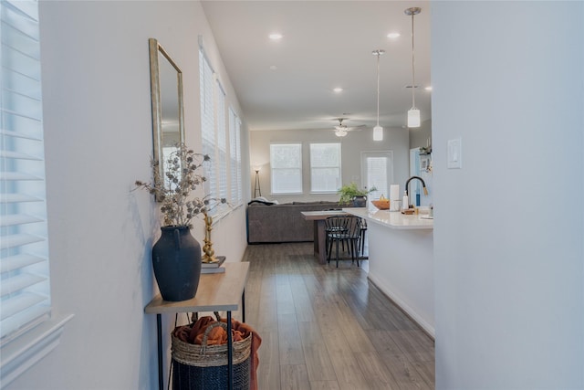 corridor featuring recessed lighting, a sink, and hardwood / wood-style flooring