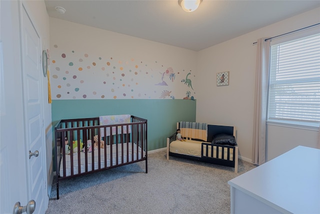 carpeted bedroom featuring a nursery area and baseboards