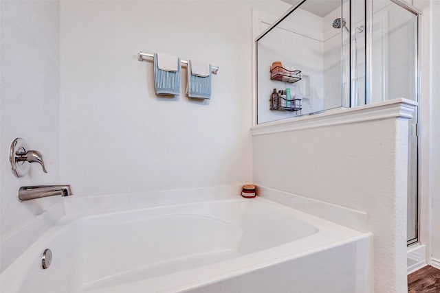 bathroom featuring a garden tub and a shower stall