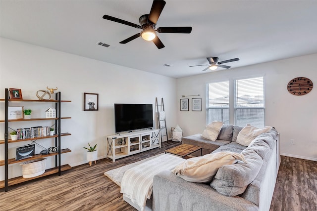 living room featuring visible vents, baseboards, and wood finished floors