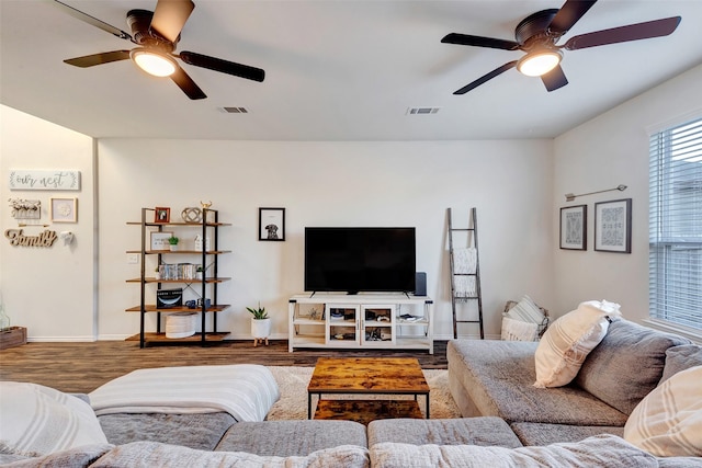 living area with ceiling fan, wood finished floors, visible vents, and baseboards