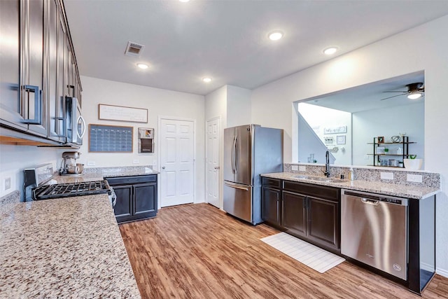 kitchen with light stone counters, a sink, visible vents, appliances with stainless steel finishes, and light wood finished floors