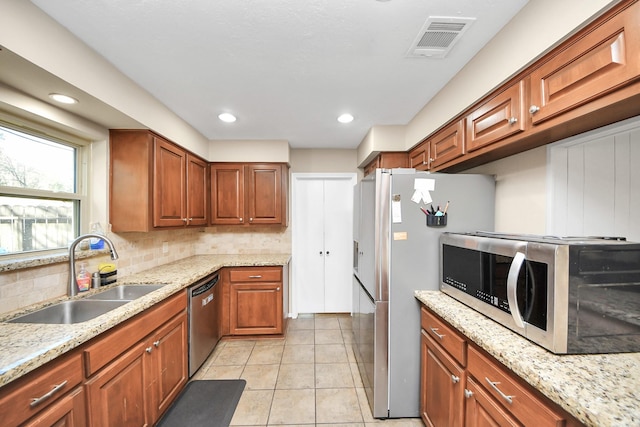 kitchen featuring light tile patterned floors, stainless steel appliances, visible vents, backsplash, and a sink