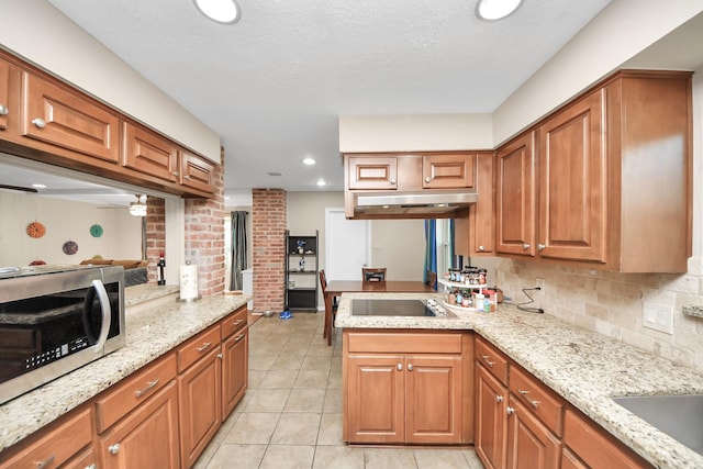 kitchen with black electric stovetop, a peninsula, brown cabinets, tasteful backsplash, and stainless steel microwave