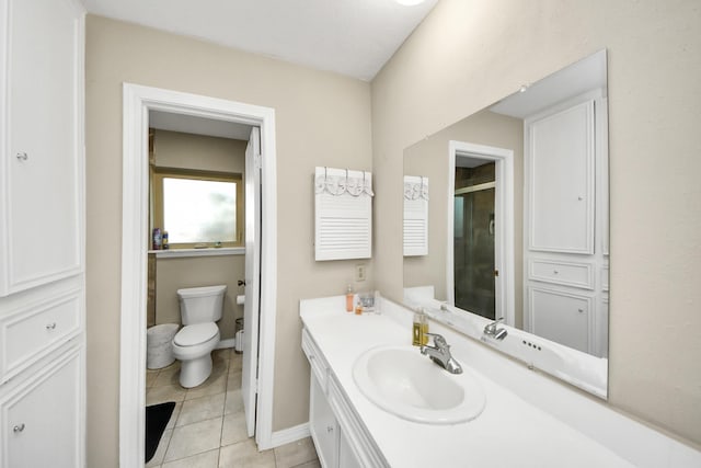 bathroom with tile patterned flooring, toilet, vanity, baseboards, and a stall shower