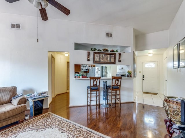 living room with ceiling fan, visible vents, and wood finished floors