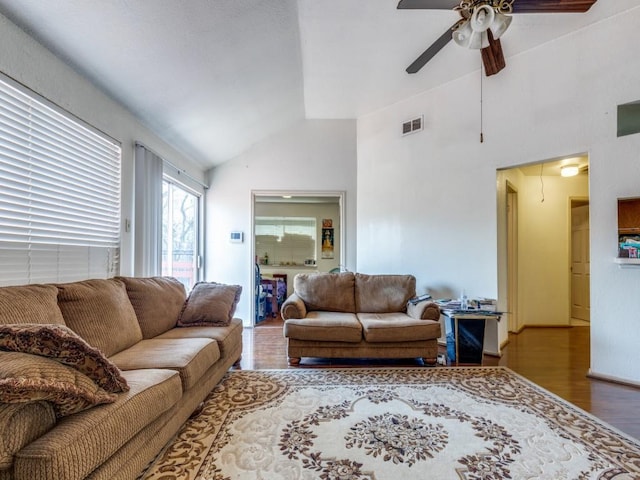 living area featuring high vaulted ceiling, wood finished floors, a ceiling fan, visible vents, and attic access