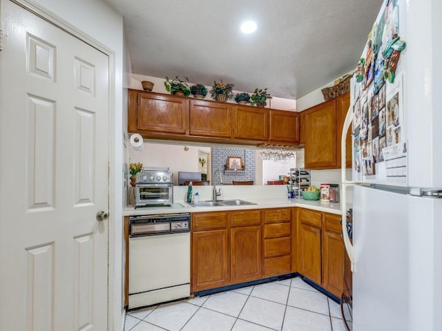 kitchen featuring white appliances, light tile patterned floors, light countertops, and a sink