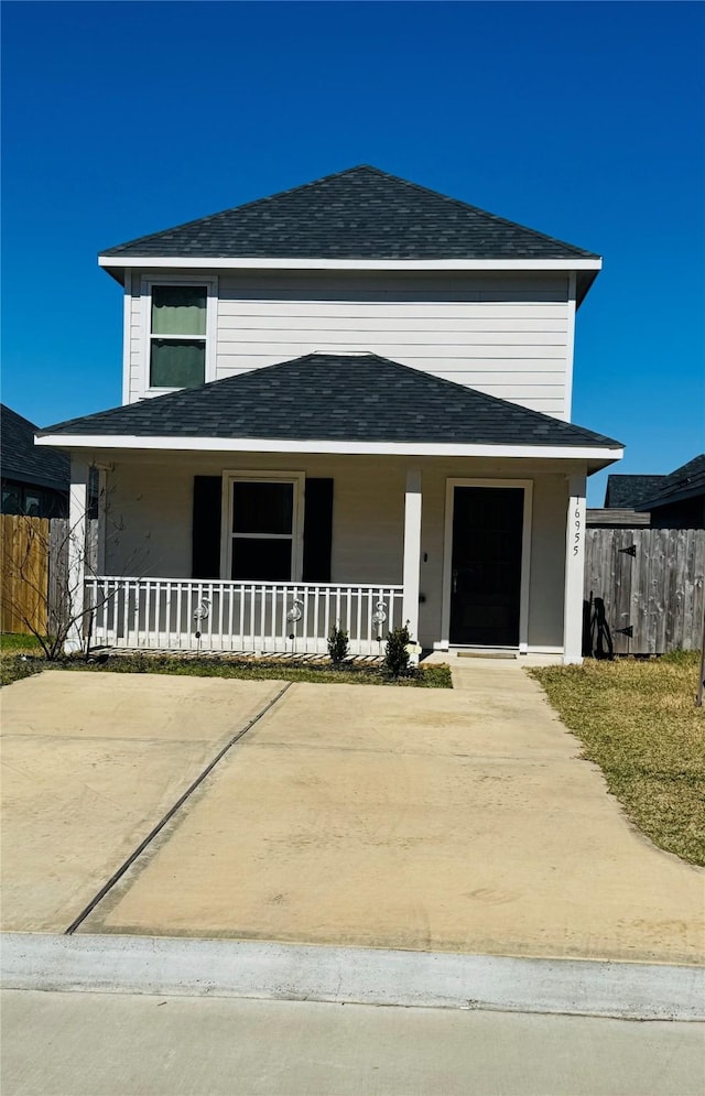 view of front facade with covered porch, fence, and roof with shingles