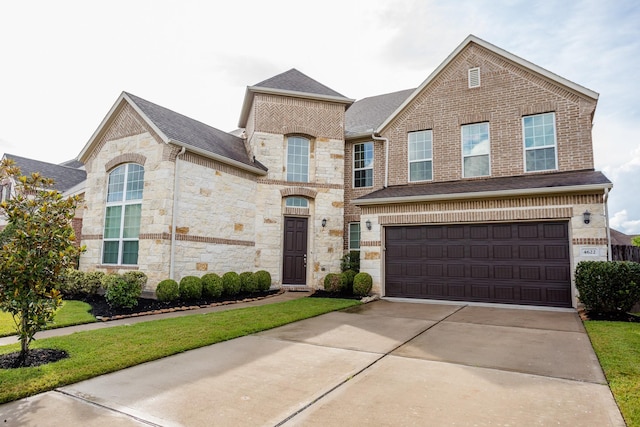 view of front of house featuring an attached garage, brick siding, driveway, stone siding, and roof with shingles