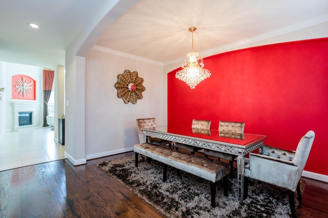 dining space featuring baseboards, ornamental molding, wood finished floors, and a glass covered fireplace