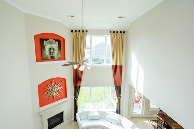 living area with crown molding, visible vents, a fireplace, and ceiling fan