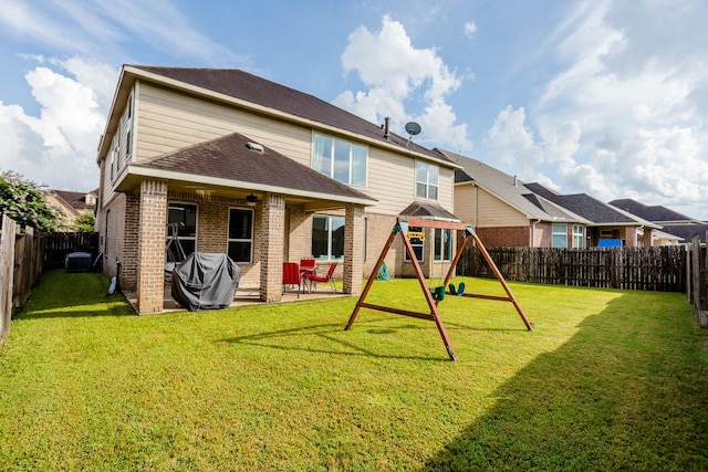 rear view of house featuring a fenced backyard, a yard, a patio area, a playground, and brick siding