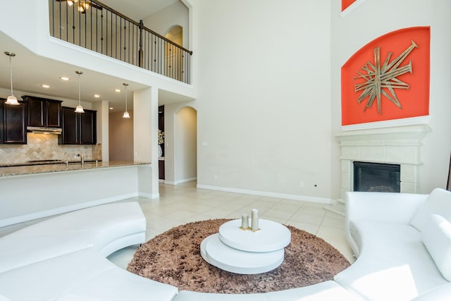 living area with light tile patterned floors, a high ceiling, baseboards, and a glass covered fireplace