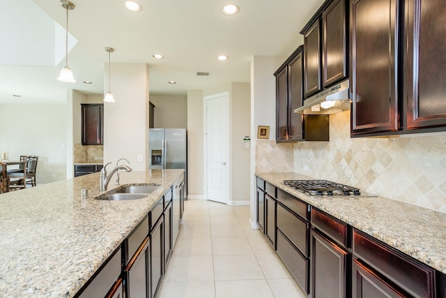 kitchen featuring visible vents, hanging light fixtures, a sink, light stone countertops, and under cabinet range hood