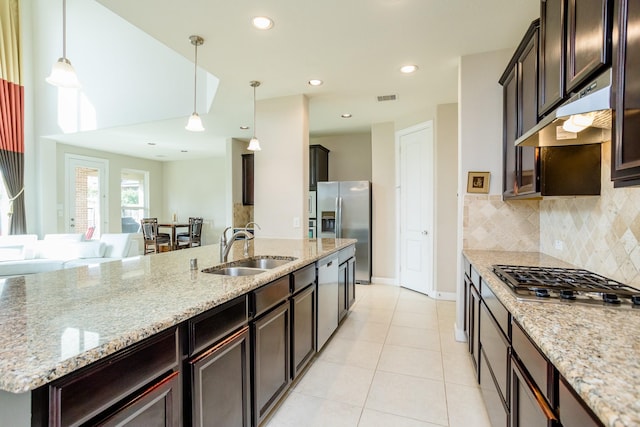 kitchen featuring under cabinet range hood, a sink, appliances with stainless steel finishes, backsplash, and decorative light fixtures