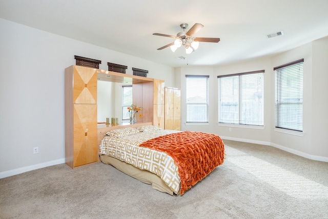 carpeted bedroom featuring a ceiling fan, visible vents, and baseboards