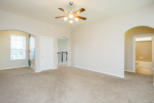 empty room with carpet flooring, a ceiling fan, and baseboards