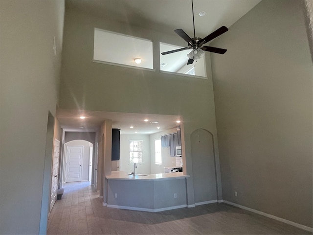 kitchen featuring arched walkways, wood finished floors, a sink, a ceiling fan, and stainless steel microwave