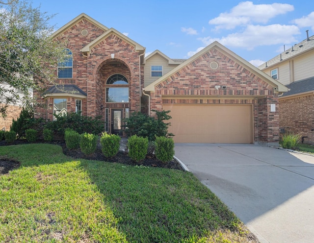 traditional-style house with a garage, driveway, a front yard, and brick siding