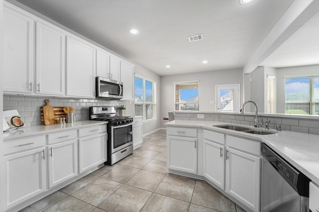 kitchen with appliances with stainless steel finishes, a sink, visible vents, and decorative backsplash