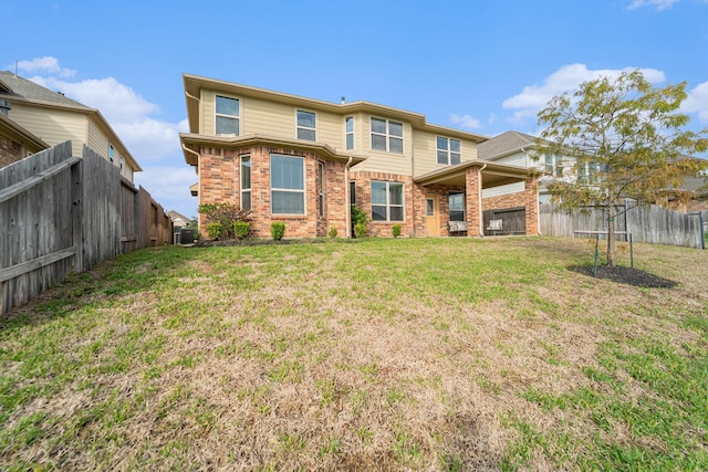 rear view of property featuring brick siding, a yard, and a fenced backyard