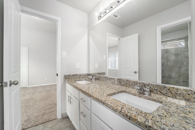 bathroom with double vanity, a sink, visible vents, and baseboards