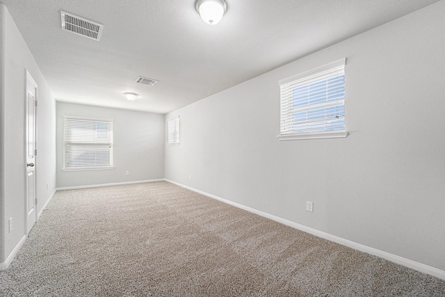 carpeted empty room with baseboards and visible vents