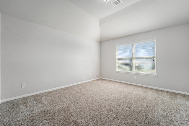 empty room with vaulted ceiling, carpet, visible vents, and baseboards