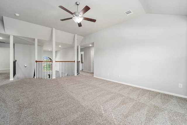 carpeted spare room with lofted ceiling, baseboards, visible vents, and a ceiling fan