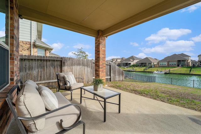 view of patio / terrace featuring a water view, a fenced backyard, a residential view, and an outdoor living space