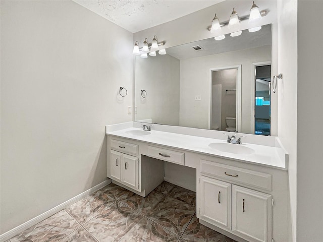 bathroom featuring toilet, double vanity, visible vents, and a sink