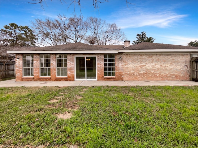 rear view of house featuring brick siding, fence, a patio, and a yard