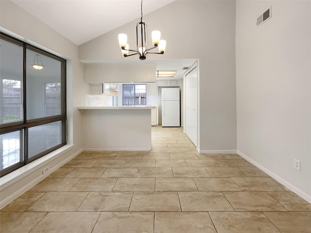 kitchen featuring lofted ceiling, a peninsula, visible vents, white cabinetry, and freestanding refrigerator