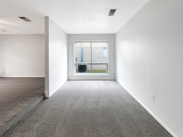 carpeted spare room with visible vents and baseboards