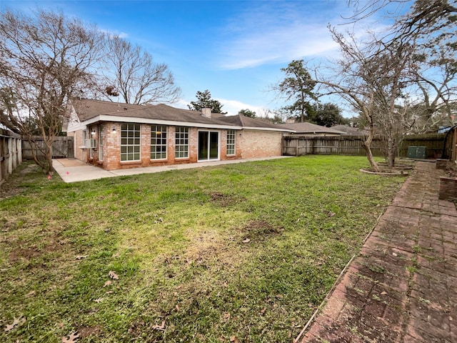 rear view of property featuring a fenced backyard, a patio, a lawn, and brick siding