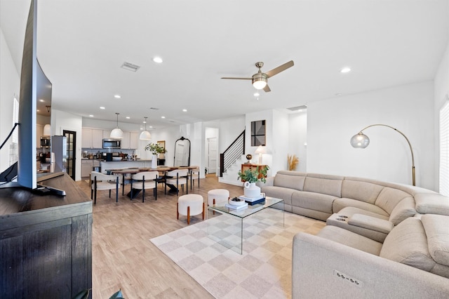 living area featuring stairway, a ceiling fan, visible vents, light wood-style flooring, and recessed lighting