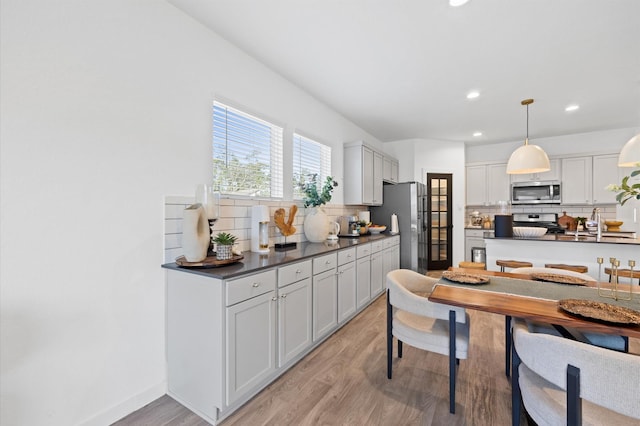 kitchen with dark countertops, decorative backsplash, stainless steel appliances, and light wood-style floors