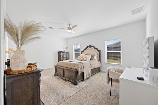 bedroom with visible vents, light colored carpet, and a ceiling fan