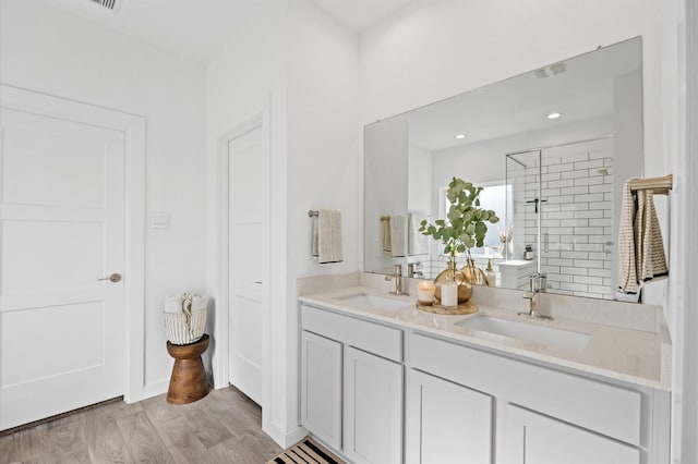 bathroom featuring a sink, double vanity, wood finished floors, and a shower stall