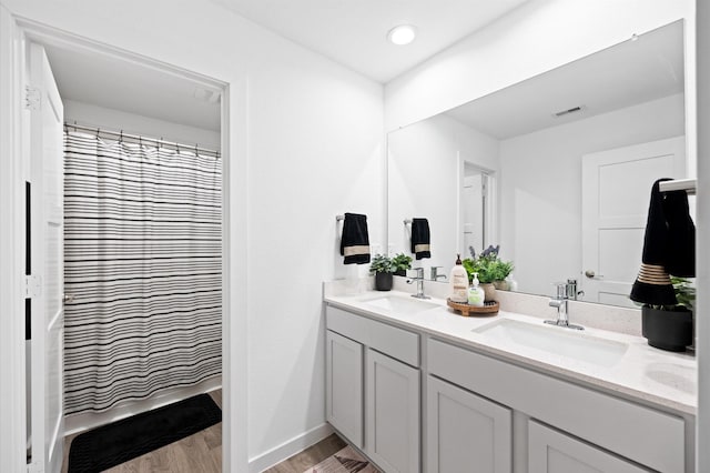 full bathroom with a sink, visible vents, wood finished floors, and double vanity