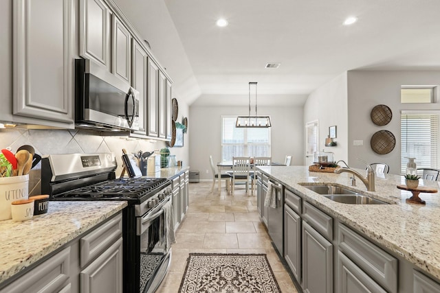 kitchen featuring visible vents, gray cabinets, a sink, decorative backsplash, and appliances with stainless steel finishes