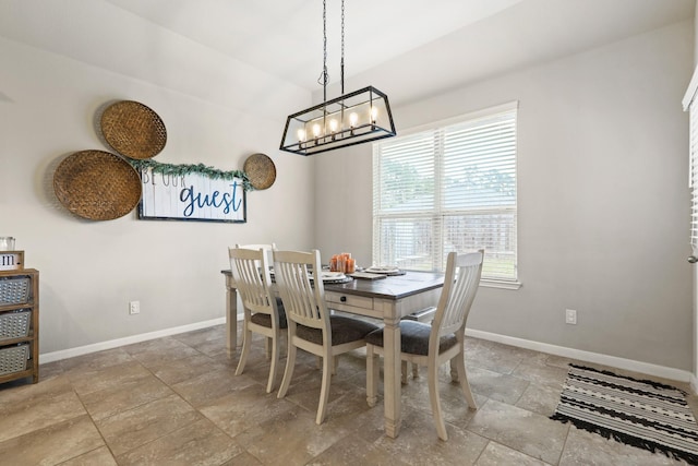 dining room featuring baseboards, lofted ceiling, a chandelier, and stone finish floor