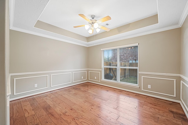 spare room featuring a raised ceiling, ceiling fan, a decorative wall, and hardwood / wood-style flooring