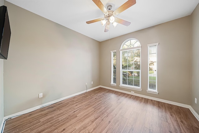 empty room featuring a ceiling fan, baseboards, and wood finished floors