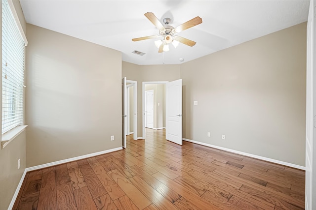 empty room featuring baseboards, a ceiling fan, visible vents, and light wood-style floors